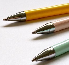 Three pastel pens on a white surface.