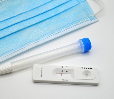 Image of a coronavirus test, plastic tube, and a blue medical facial mask.