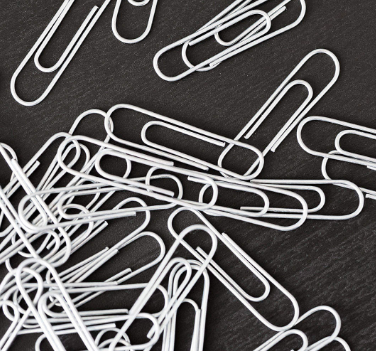 Paperclips scattered on a dark wood surface.